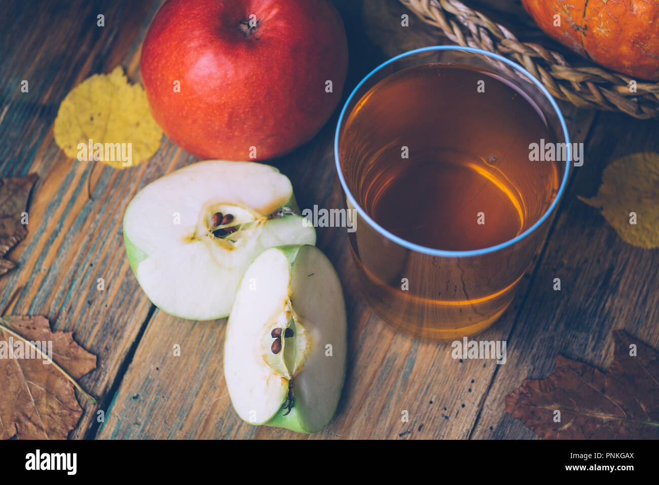 Cold apple cider or apple juice with fresh apples on a wooden background. Autumn drinks. Autumn mood Stock Photo
