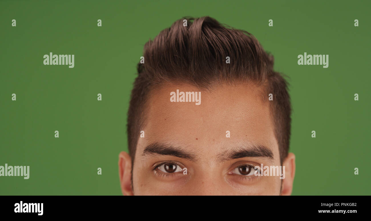 Close up of Hispanic man with cool undercut on green screen Stock Photo