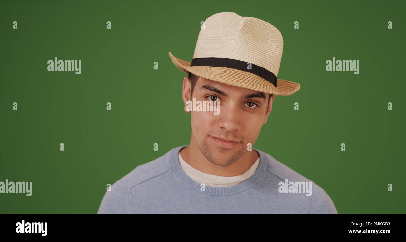 Handsome millennial Latino man wearing fedora on green screen Stock Photo