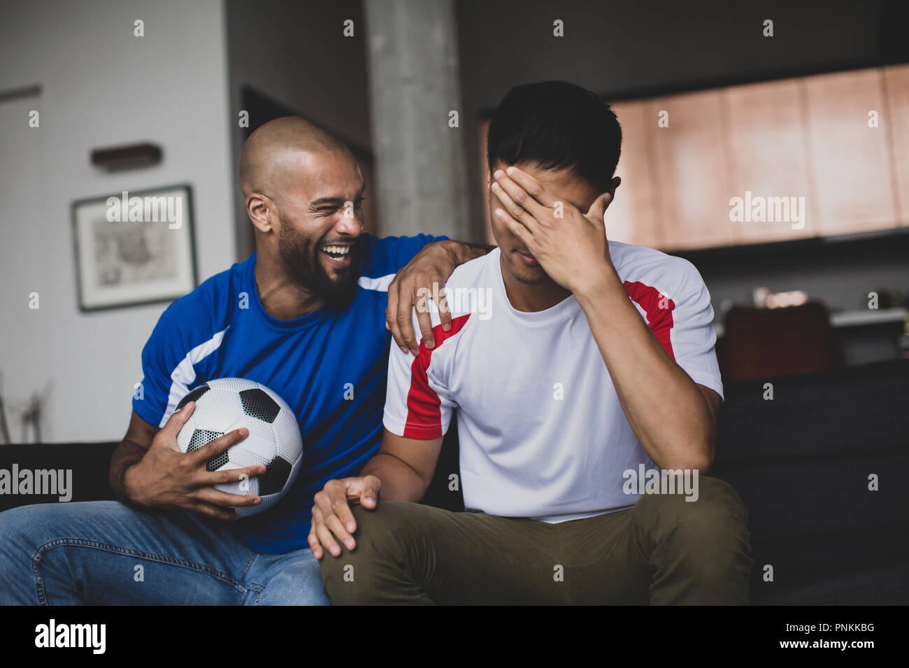 Male friends watching a football match Stock Photo