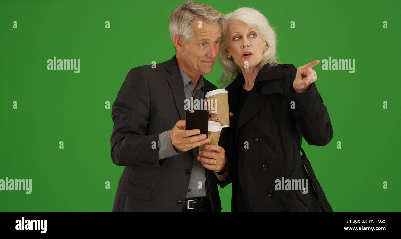 Modern seniors using smartphone to get directions on green screen Stock Photo