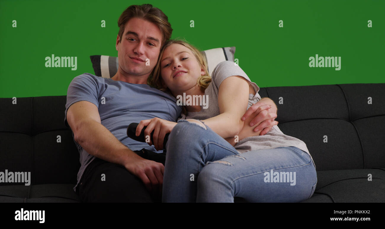 Young Couple Cuddling On Sofa Watching Television Or Movie On