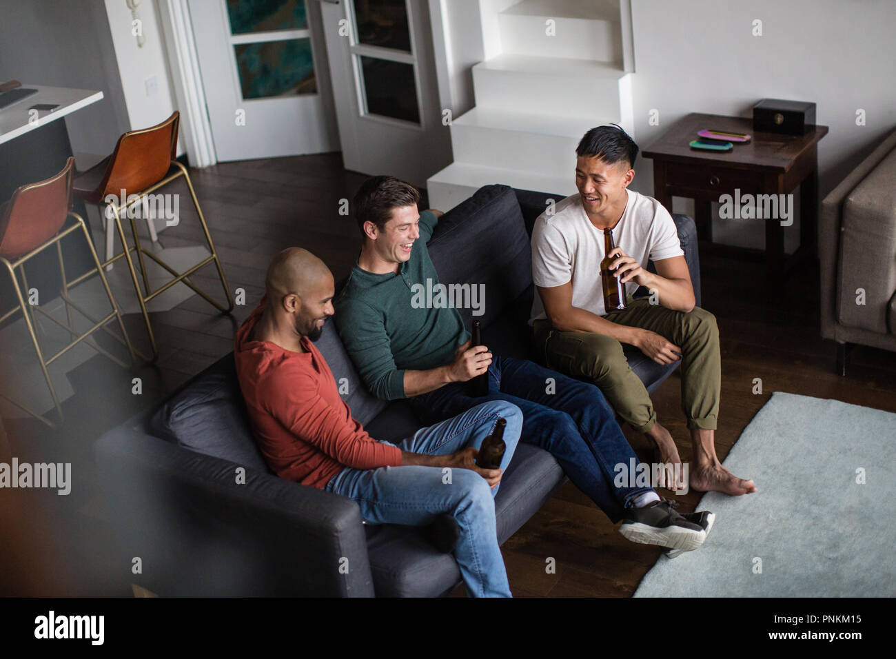 Male friends having a beer together in an apartment Stock Photo