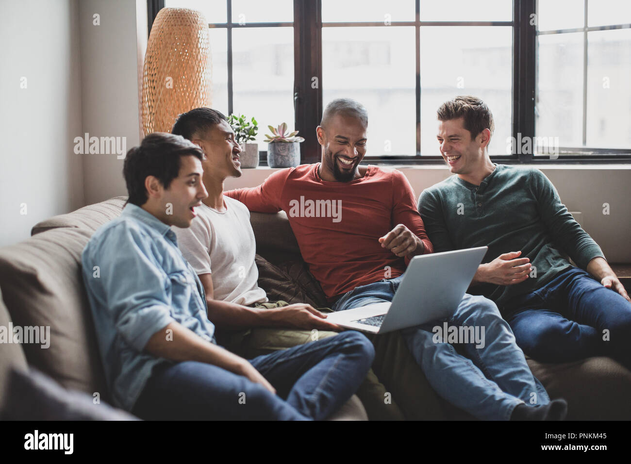 Group of male friends watching video on laptop Stock Photo