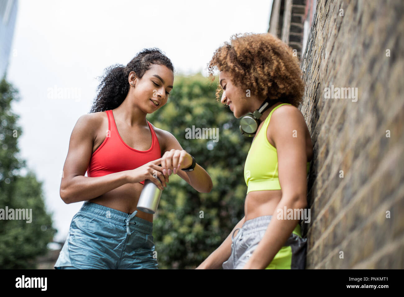 Young adult females taking a break on a run in urban city Stock Photo