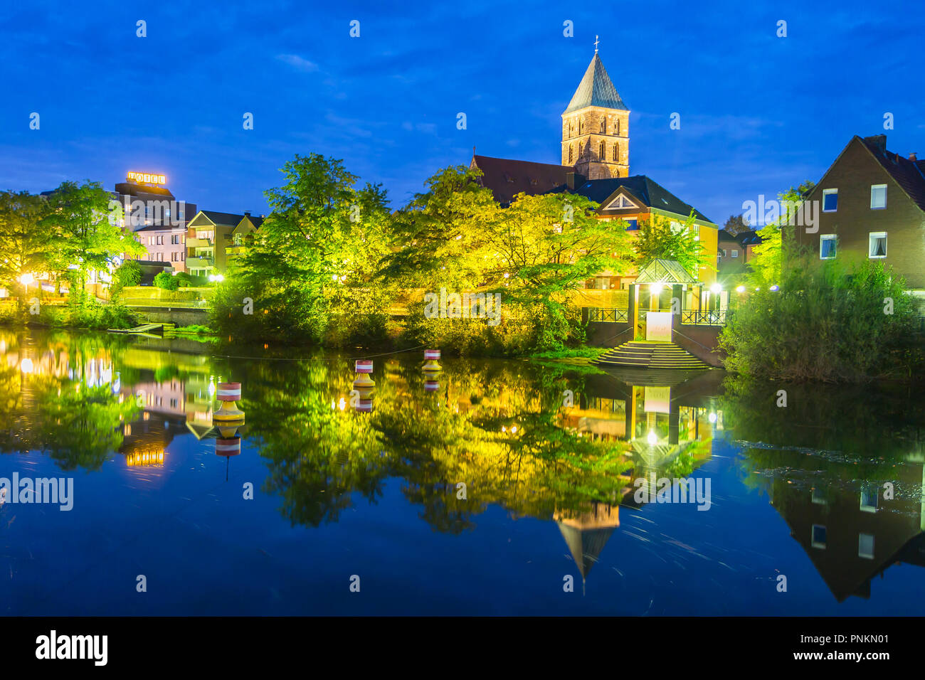Rheine, Germany - September 5, 2018: night view belfry tower of medieval Sankt Antonius Basilica reflecting on in the still waters of Ems river Stock Photo