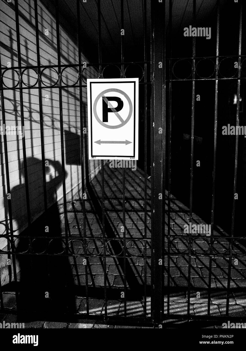 No parking sign on an entrance gate at night with shadows Stock Photo