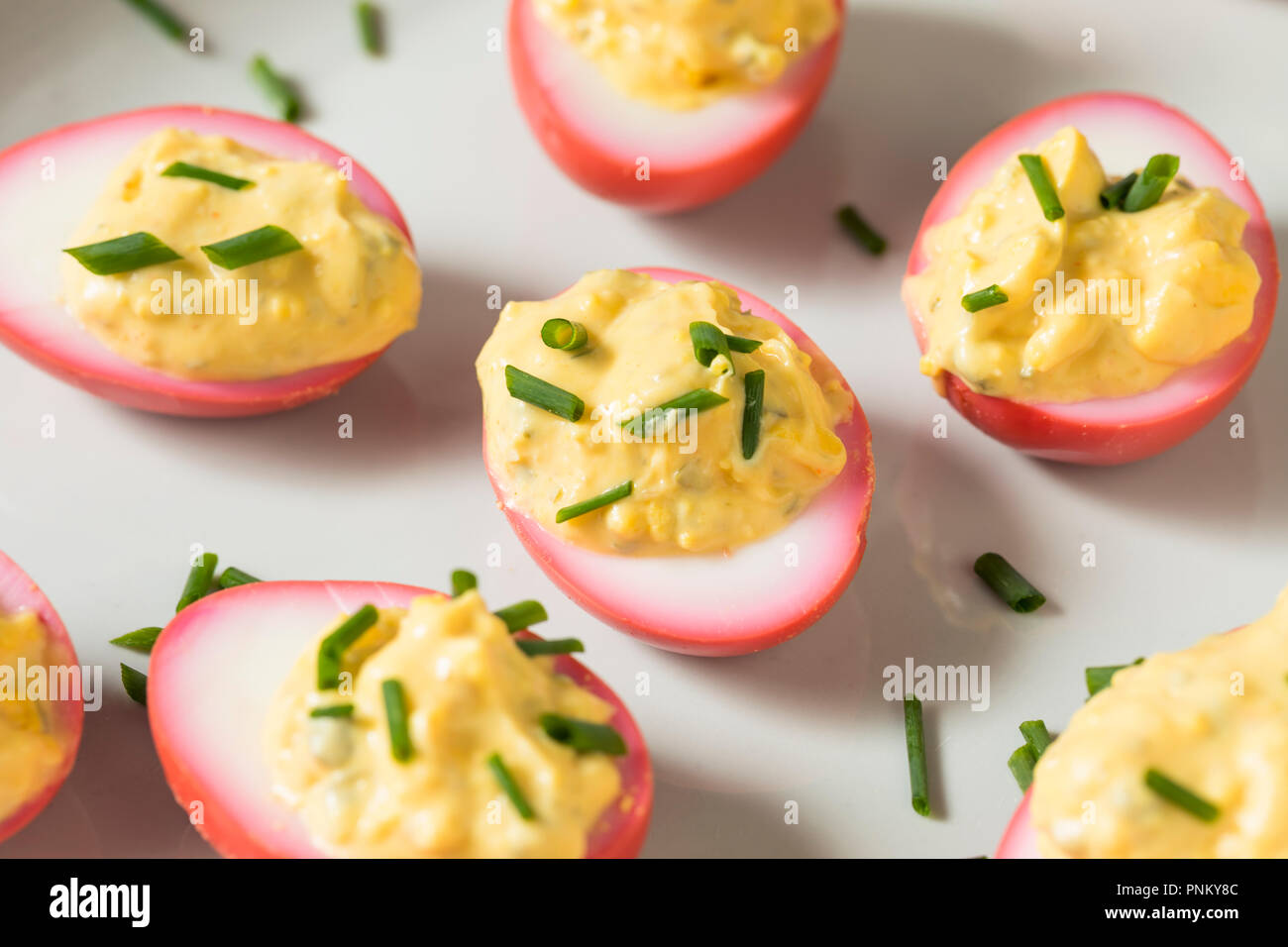 Homemade Pink Pickled Deviled Eggs with Chives Stock Photo