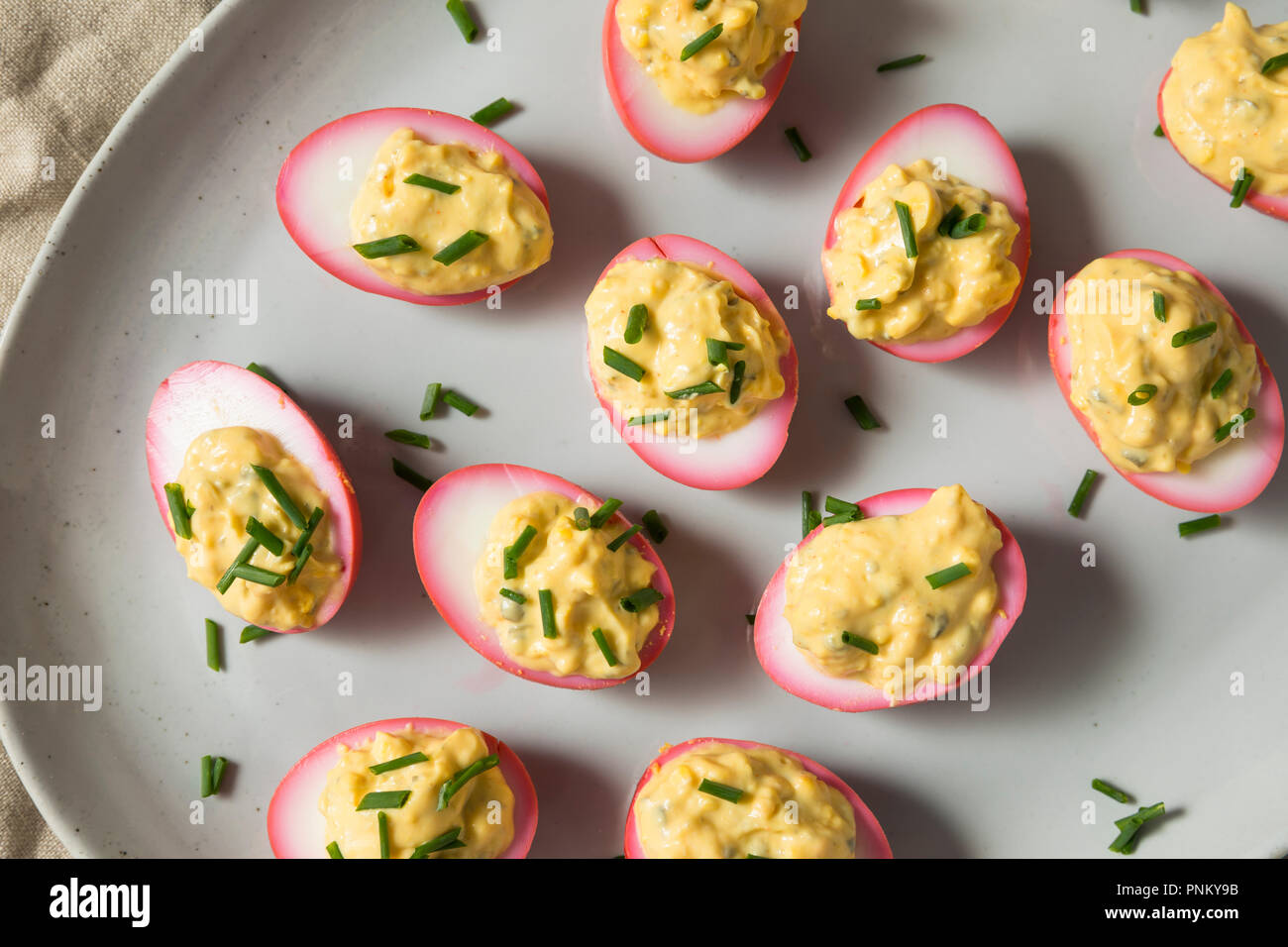 Homemade Pink Pickled Deviled Eggs with Chives Stock Photo
