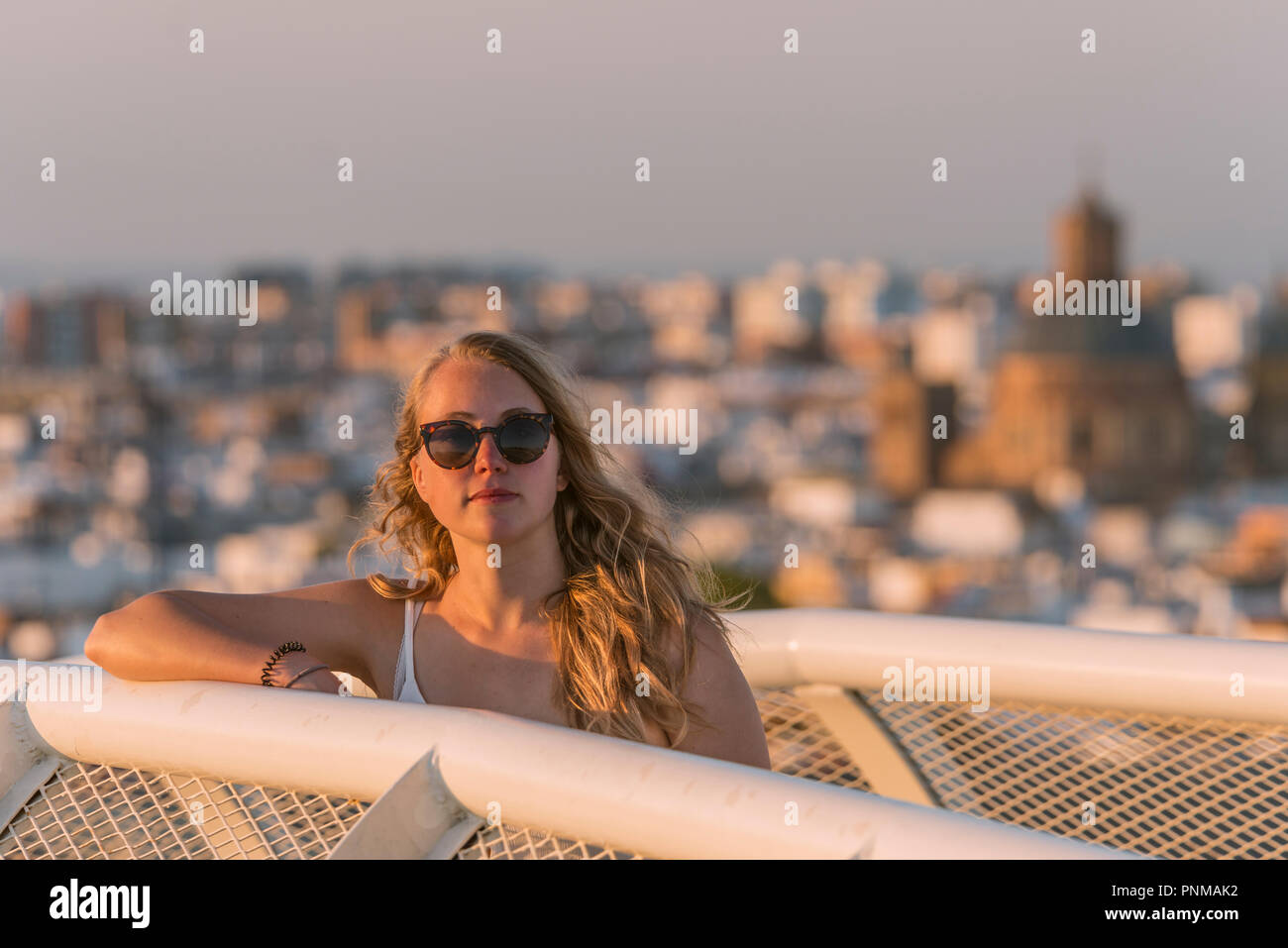 Young woman in sunglasses looks into the camera, Plaza de la Encarnacion, behind houses, Seville, Andalusia, Spain Stock Photo