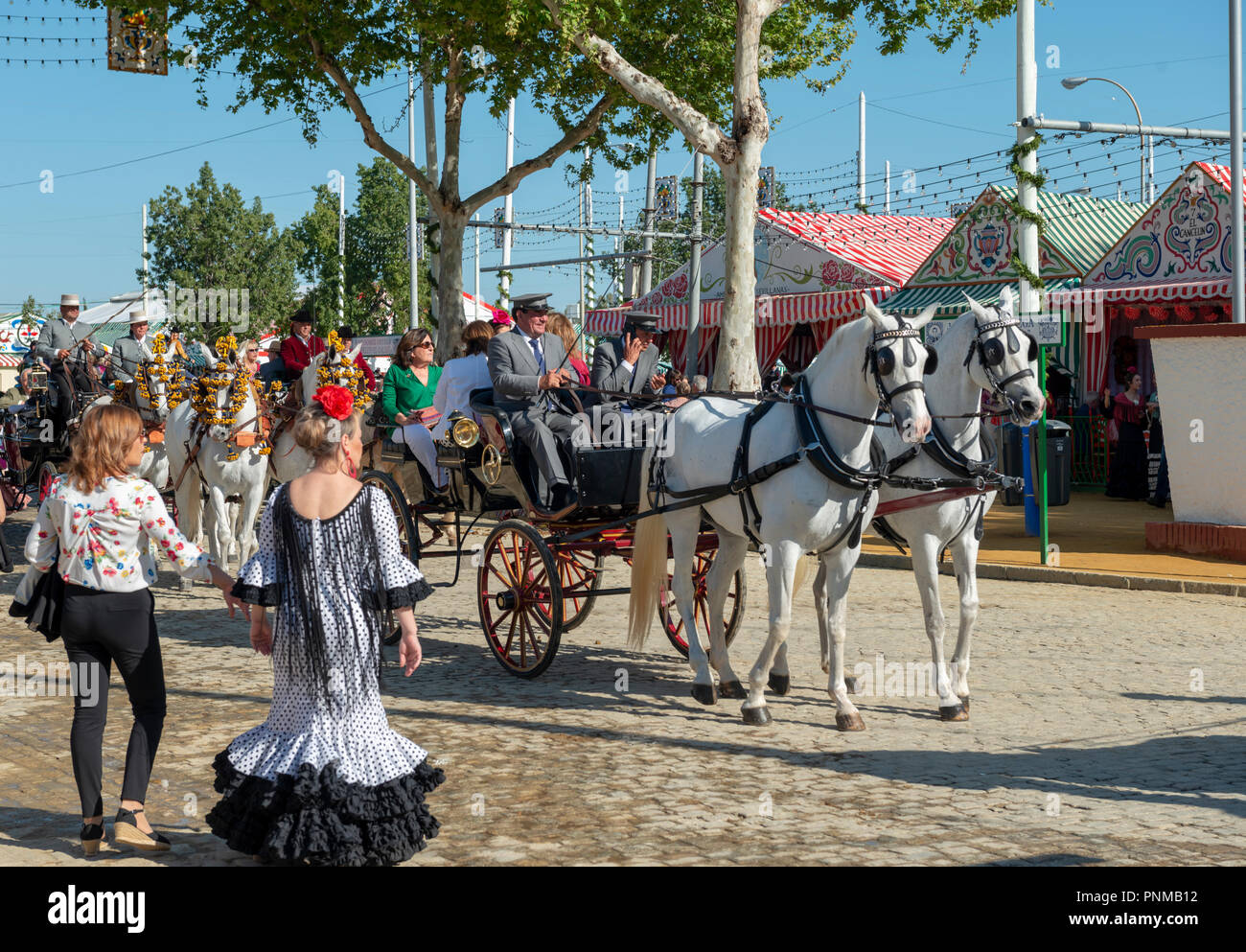 Spaniard in traditional flamenco dresses, decorated horse-drawn carriage in front of Casetas, Feria de Abril, Sevilla, Andalusia Stock Photo