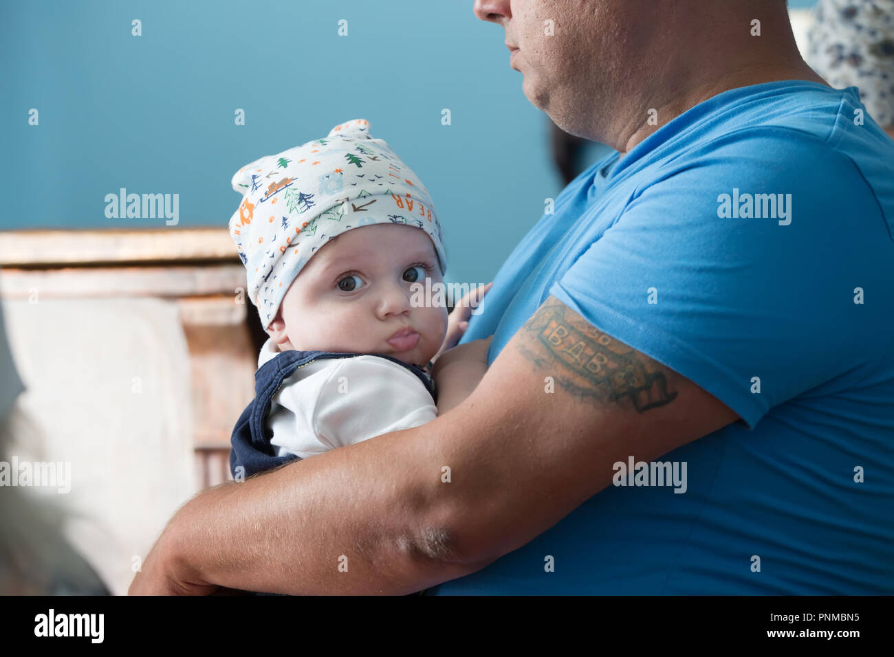 Belarus, Gomel, July 2, 2016. The Church of Zyabrovskaya. A brutal father with a tattoo on his arm holds a baby Stock Photo