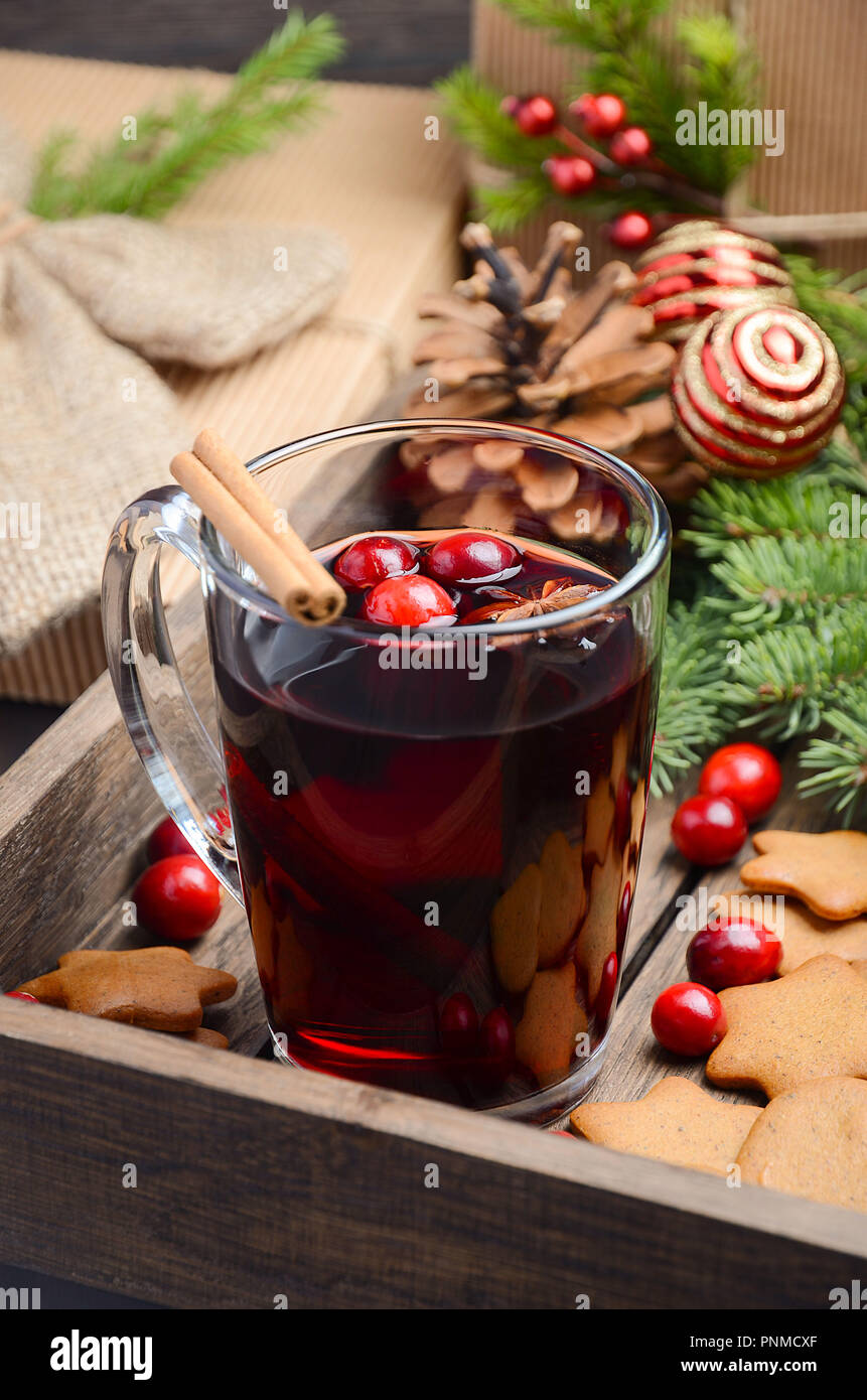 Christmas mulled wine. Holiday concept decorated with Fir branches, Gingerbread Cookies and Cranberries on dark wooden tray. Stock Photo