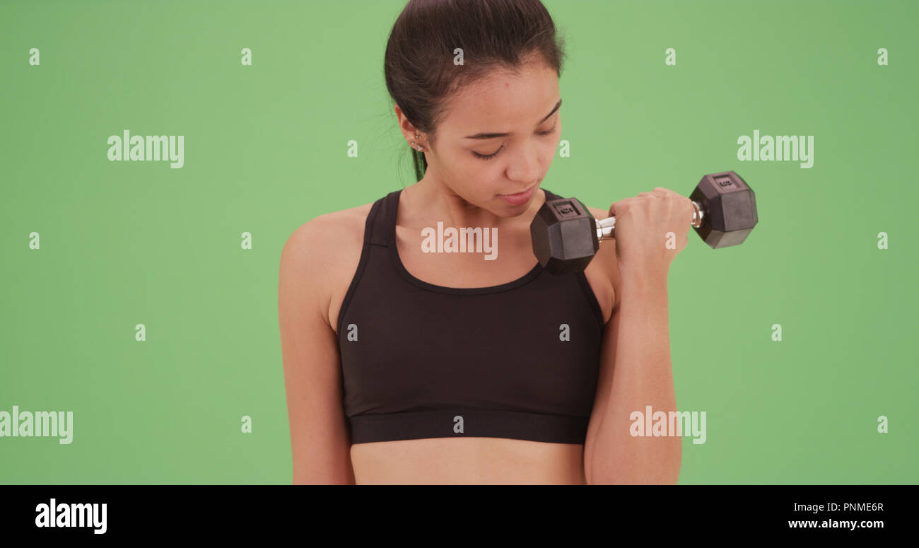 Young latina lifting small dumbbells on greens screen Stock Photo - Alamy