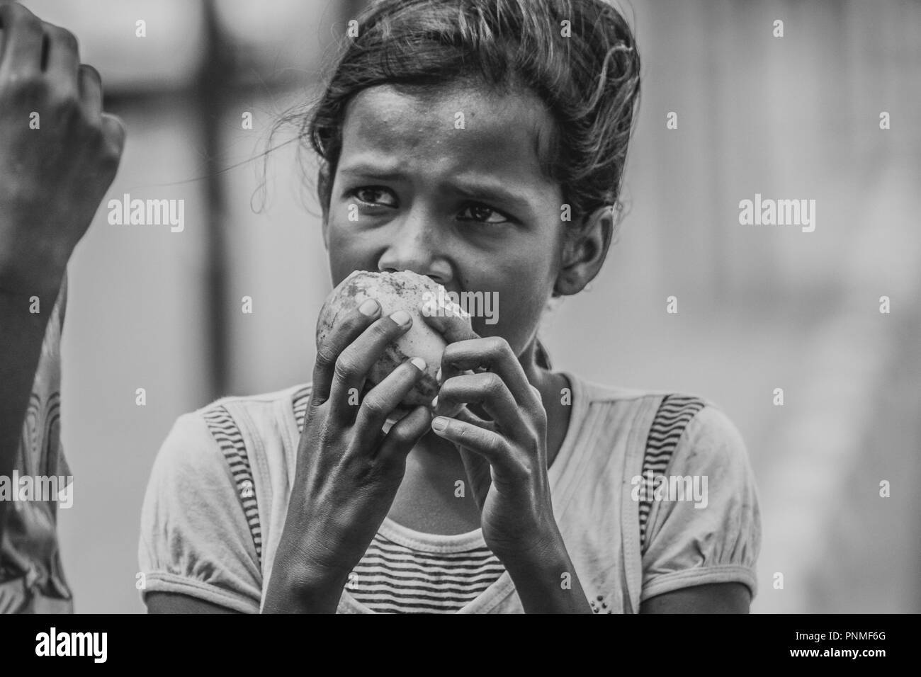 Sri Lankan poor street girl eating a mango at Tissamaharama Stock Photo