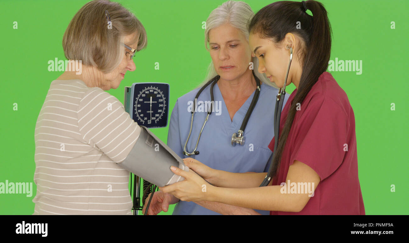 RN student to take senior patient blood pressure on green screen Stock Photo