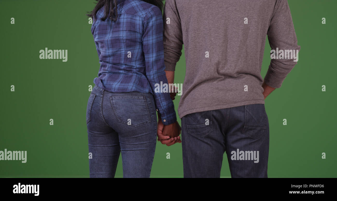 Rear view of young black couple holding hands on green screen Stock ...
