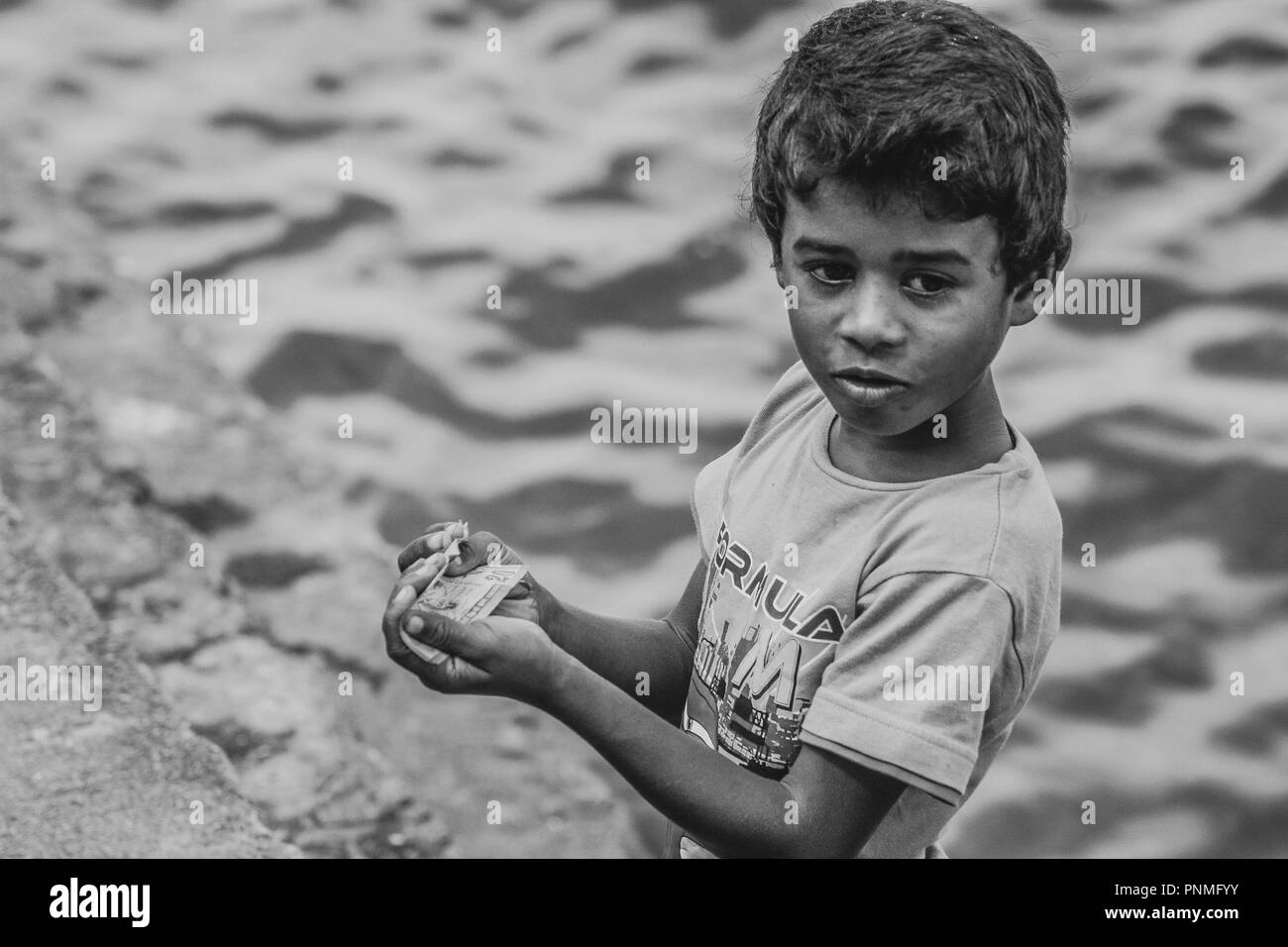 Sri lankan poor street kid counting money at Tissamaharama Stock Photo