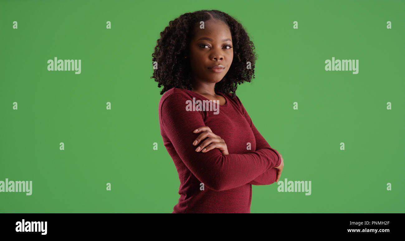 Confident African American woman posing with arms crossed on green ...