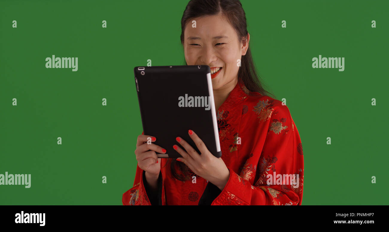 Asian woman in traditional silk garment with tablet device on green screen Stock Photo