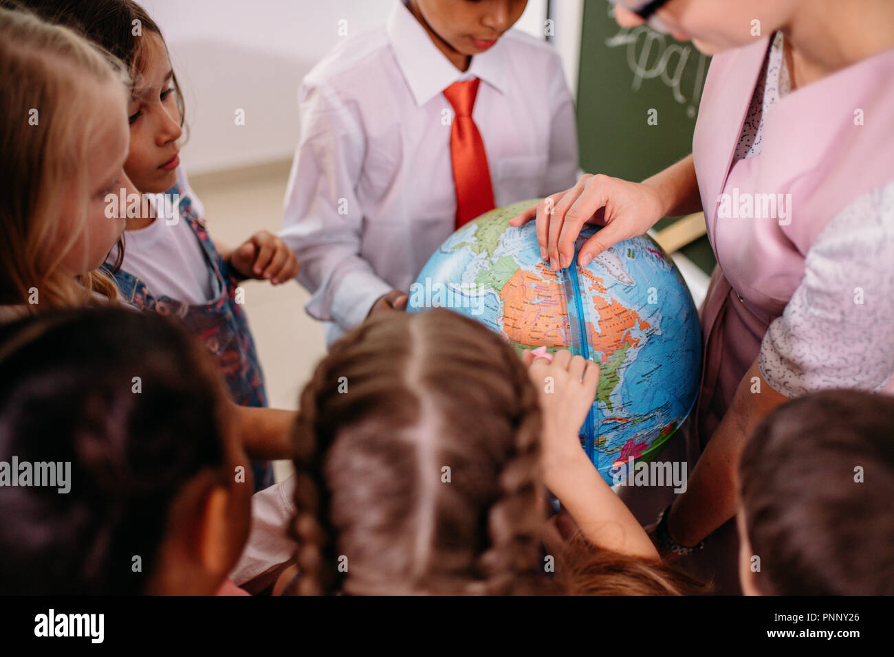 schoolchilds looking at globe with teacher at geography lesson Stock Photo