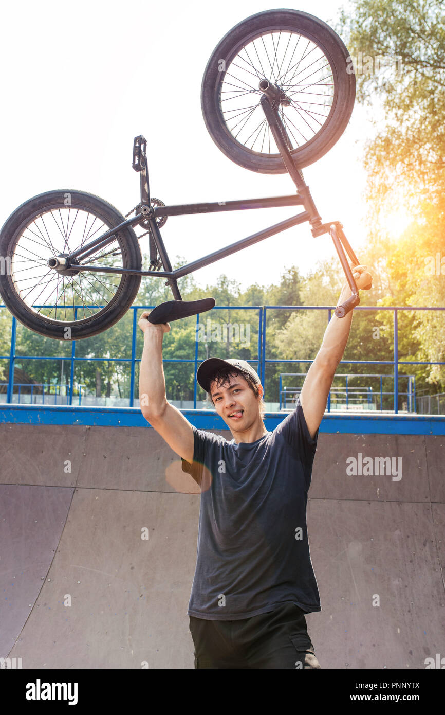 man holding bmx bicycle above head and smiling at camera Stock Photo - Alamy