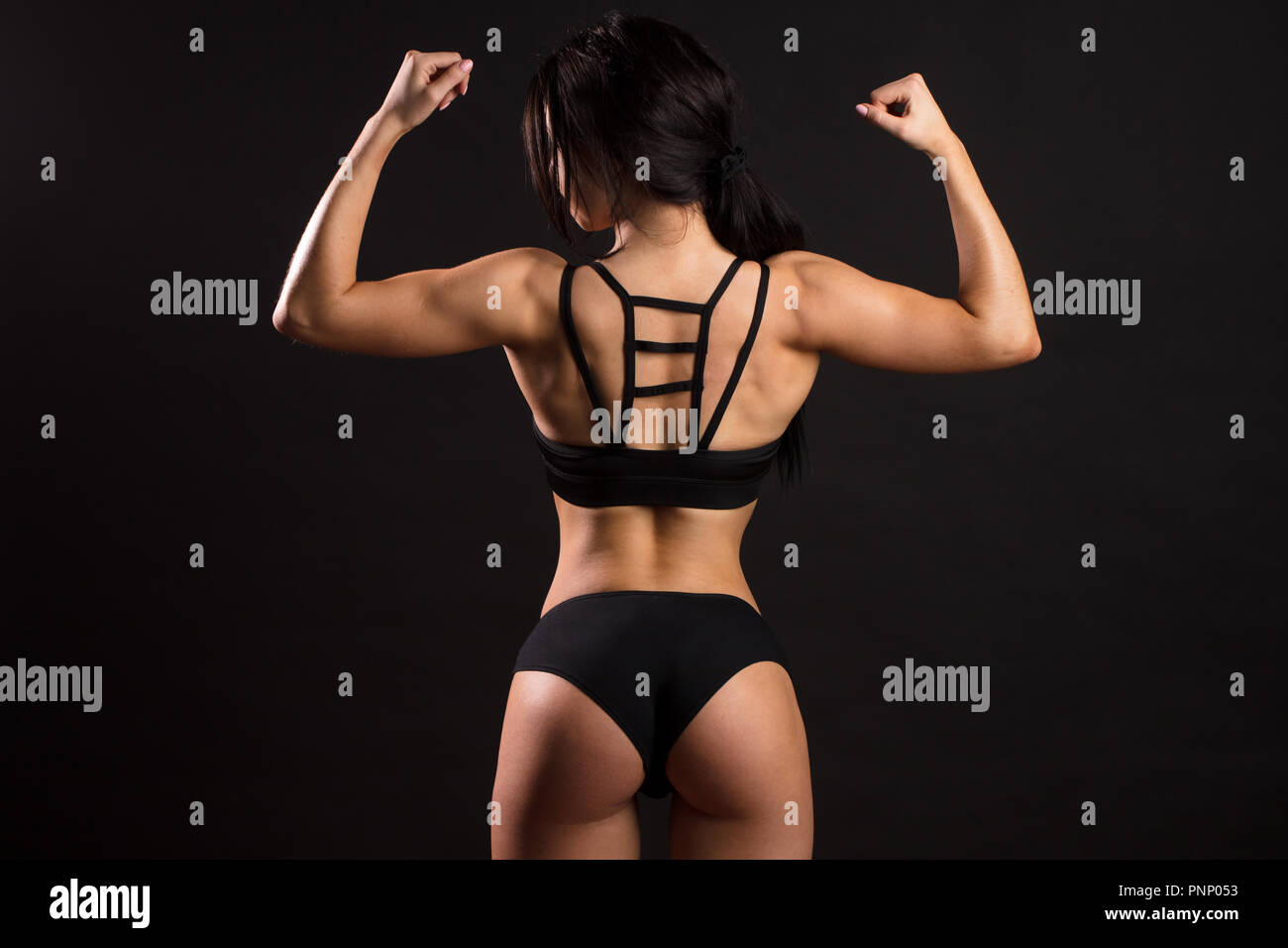 Rear view of woman with muscular body. Fitness female showing