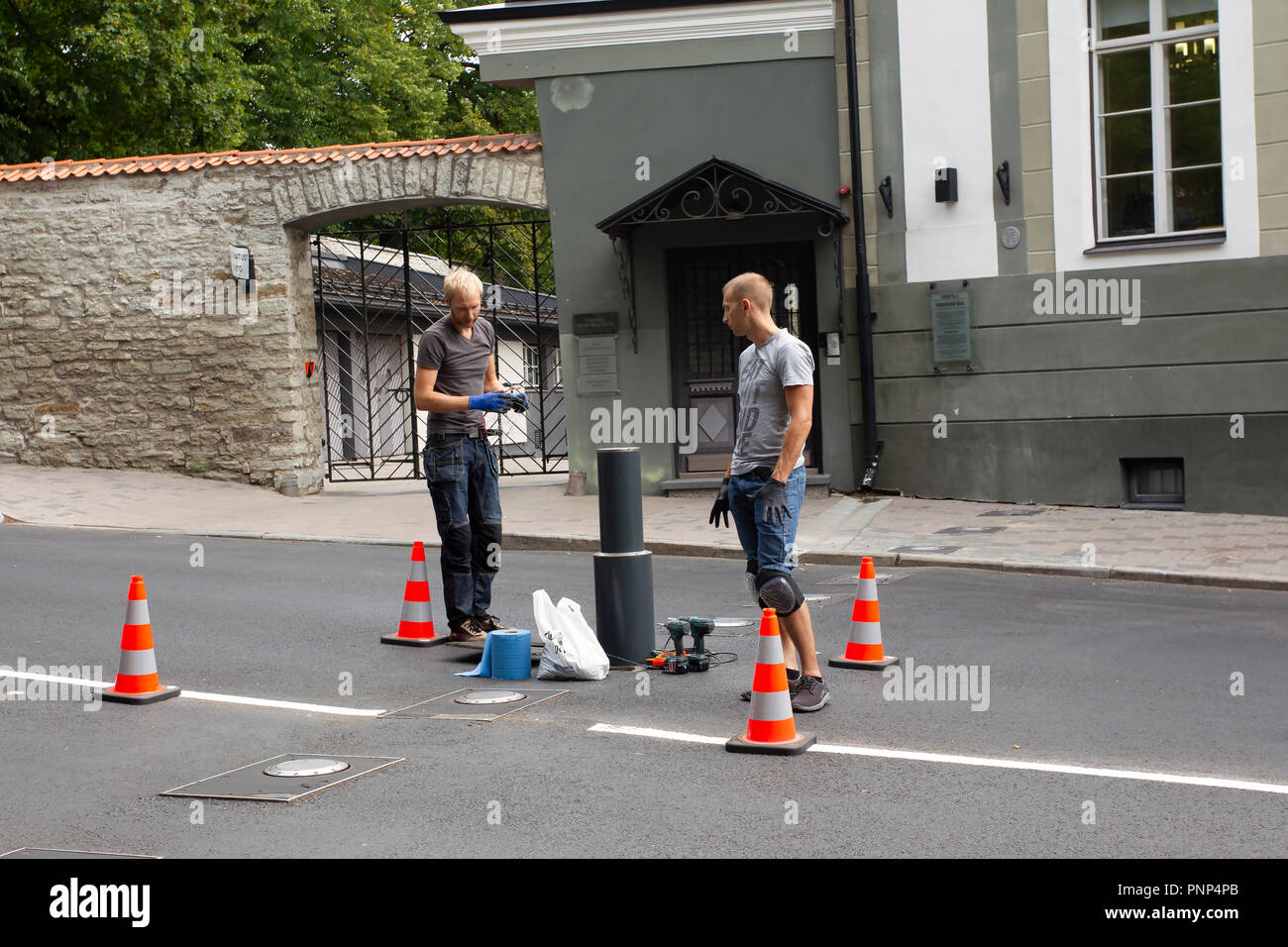 Two Men Working on Retractable Security Barrier Stock Photo