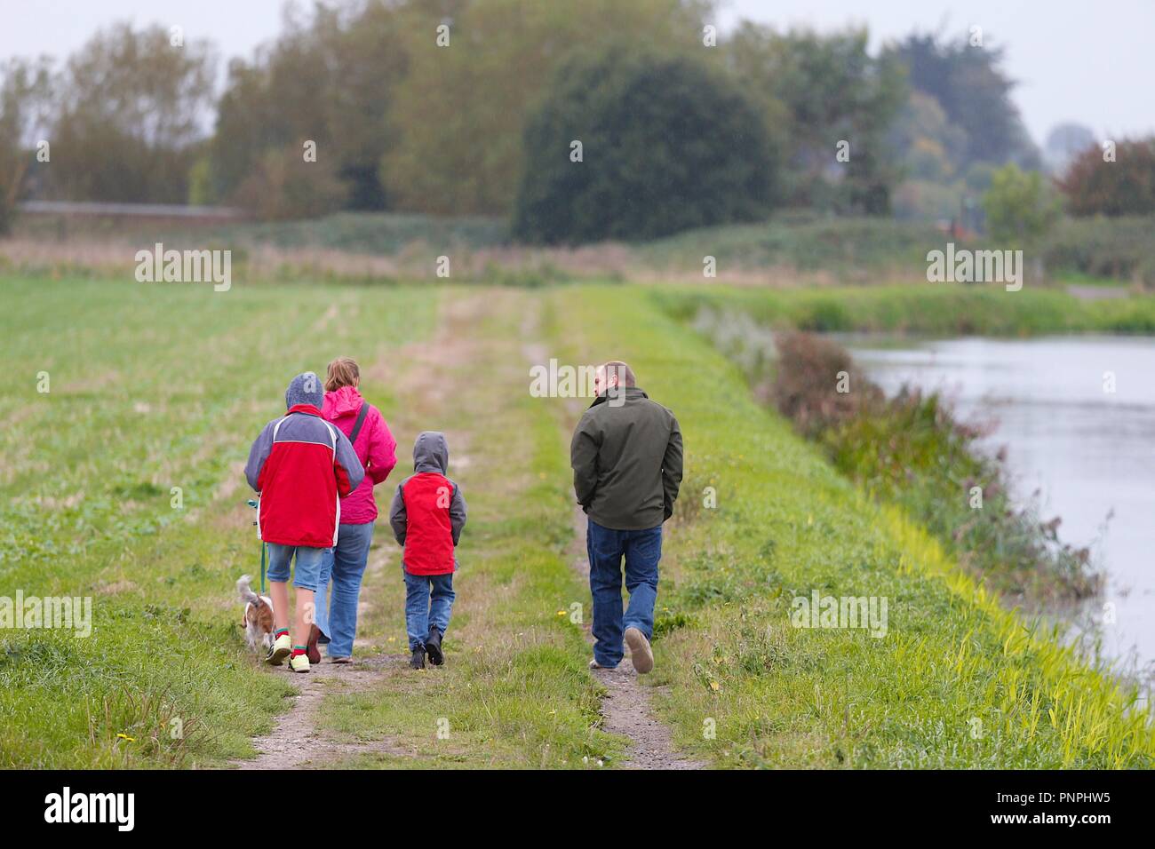 Ashford, Kent, UK. 22th Sep, 2018. UK Weather: The unsettled weather continues as it starts to pour down with rain in the village of Hamstreet just outside Ashford. A family in bright red jackets walk a dog in the pouring rain along a path beside a rural sewer ditch canal. © Paul Lawrenson 2018, Photo Credit: Paul Lawrenson / Alamy Live News Stock Photo