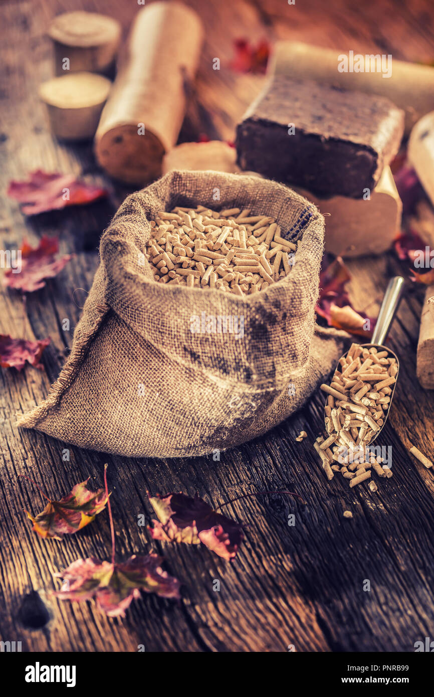Wooden pressed pellets and briquettes from biomass with autumn leaves. Stock Photo