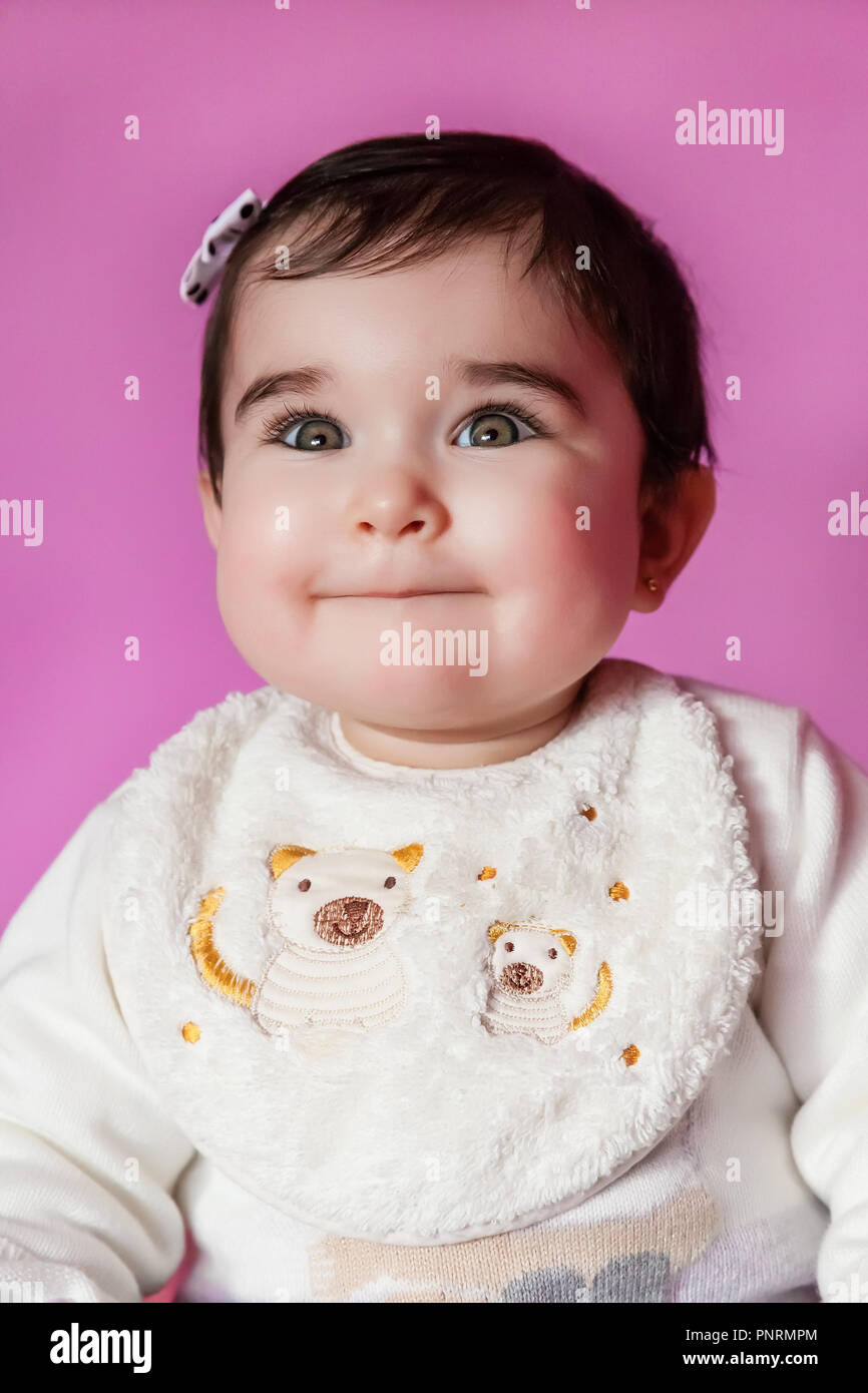 Cute, pretty and happy baby girl smiling portrait wearing a bow in hair. Nine months old Stock Photo