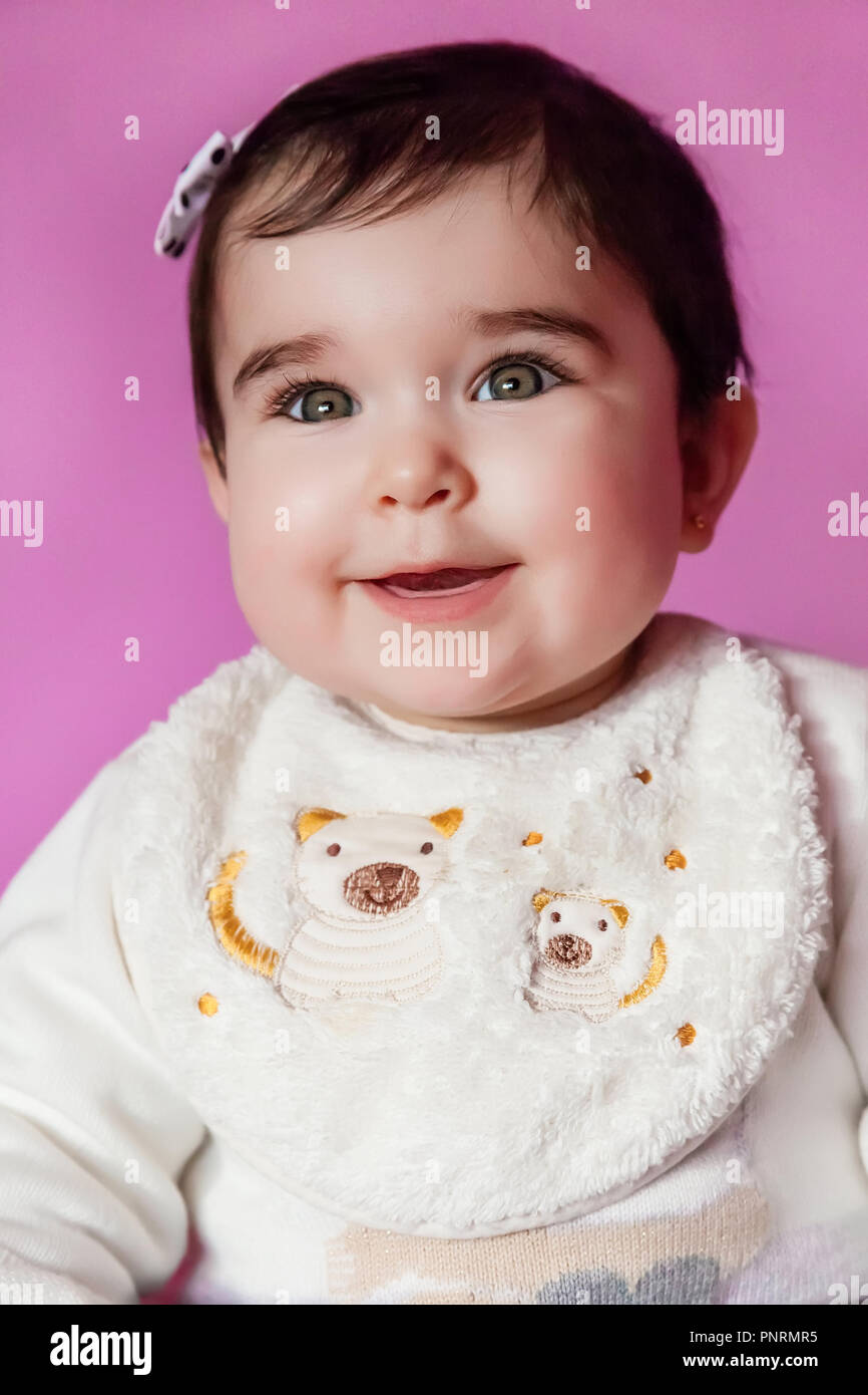 Cute, pretty and happy baby girl smiling portrait wearing a bow in hair. Nine months old Stock Photo