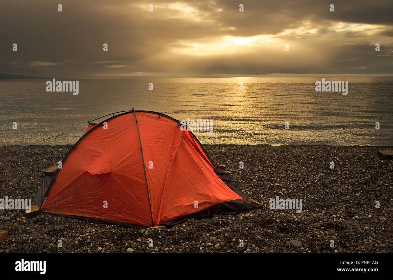Tent near lake shore at the beautiful sunset Stock Photo