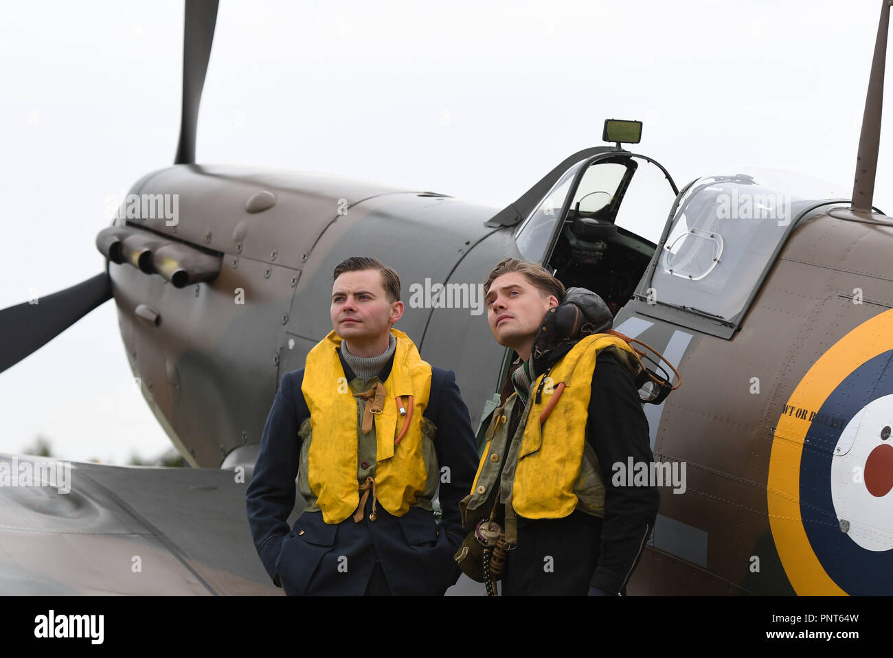 Historical reenactment members Jamie Delaney (right) and Gary Lewis from Spirit of Britain stand on the flight line in front of a Supermarine Spitfire prior to the Battle of Britain Air Show at the Imperial War Museum in Duxford, Cambridgeshire. Stock Photo