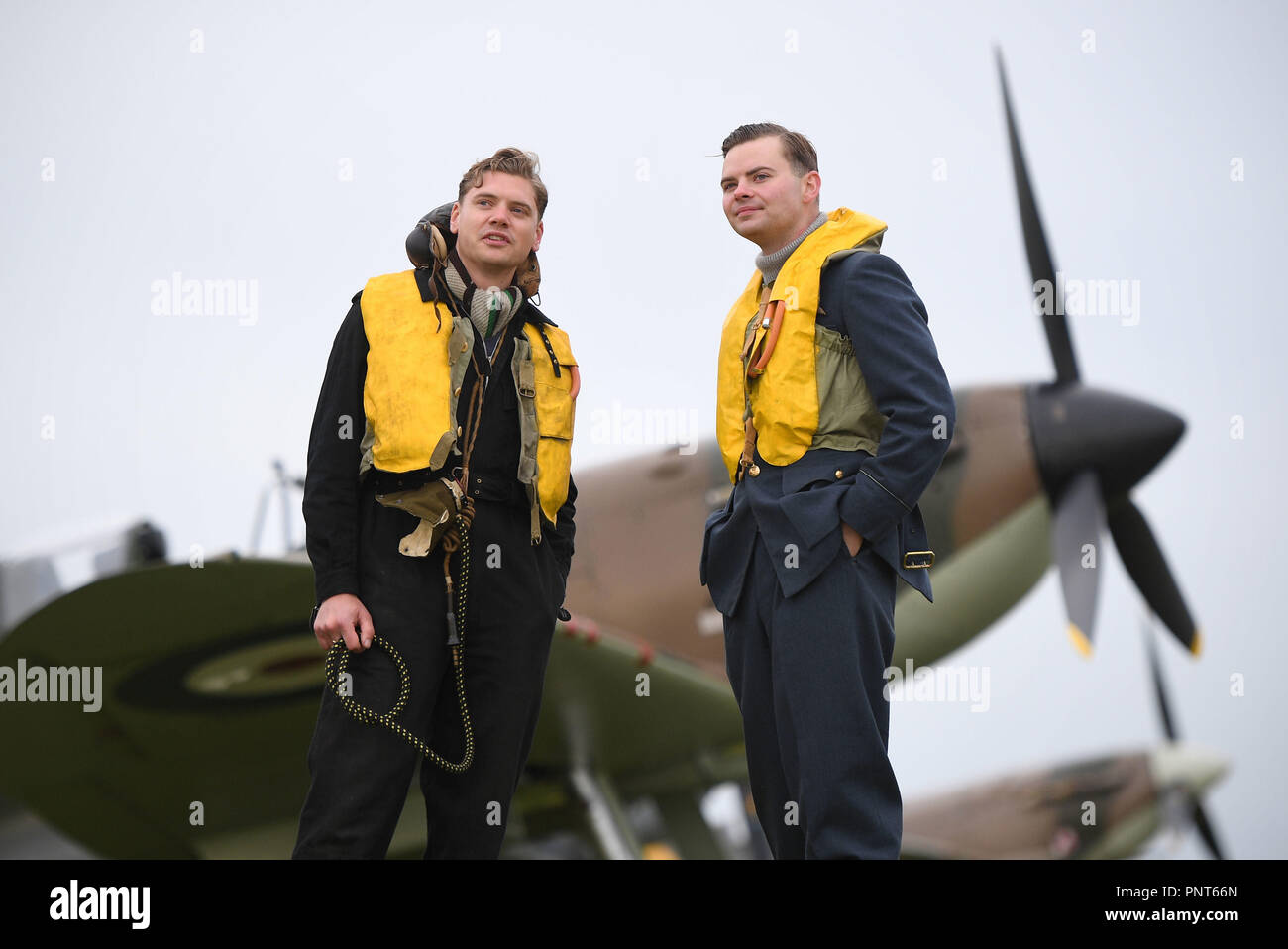 Historical reenactment members Jamie Delaney (left) and Gary Lewis from Spirit of Britain stand on the flight line in front of a Supermarine Spitfire prior to the Battle of Britain Air Show at the Imperial War Museum in Duxford, Cambridgeshire. Stock Photo