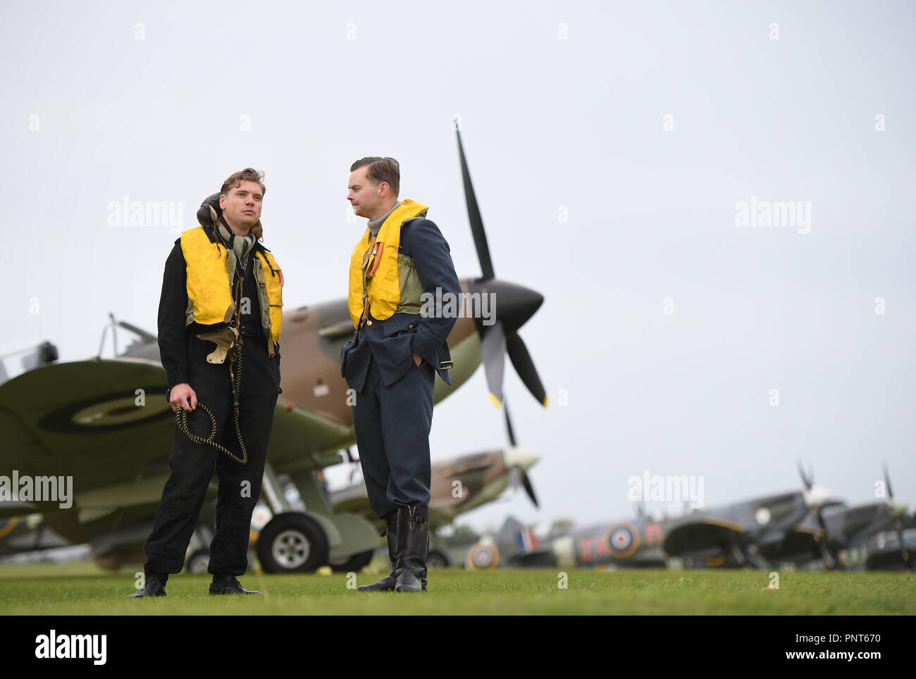 Historical reenactment members Jamie Delaney (left) and Gary Lewis from Spirit of Britain stand on the flight line in front of Supermarine Spitfires prior to the Battle of Britain Air Show at the Imperial War Museum in Duxford, Cambridgeshire. Stock Photo
