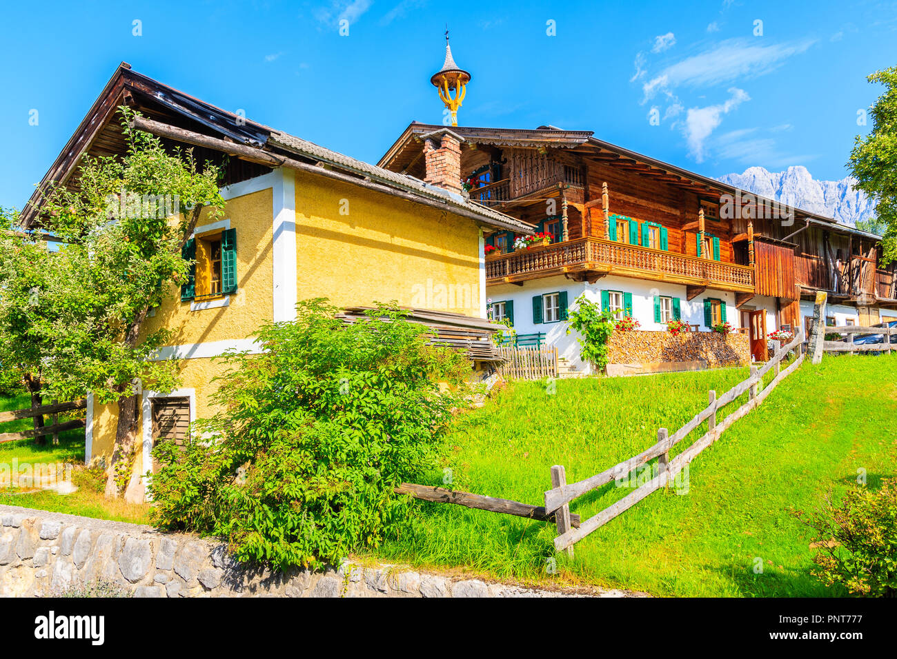 Typical wooden alpine houses on green meadow in Going am Wilden Kaiser village on sunny summer day, Tyrol, Austria Stock Photo