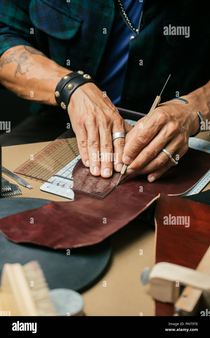 Leather goods master and handmade leather wallets. Workflow in the workshop. Stock Photo