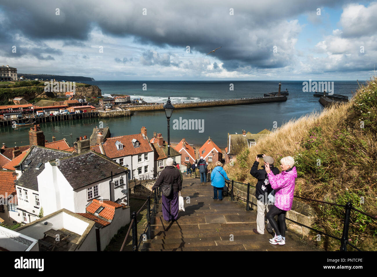 The steps up to the Abbey and view of the harbour entrance at Whitby, Yorkshire with rain threatening Stock Photo