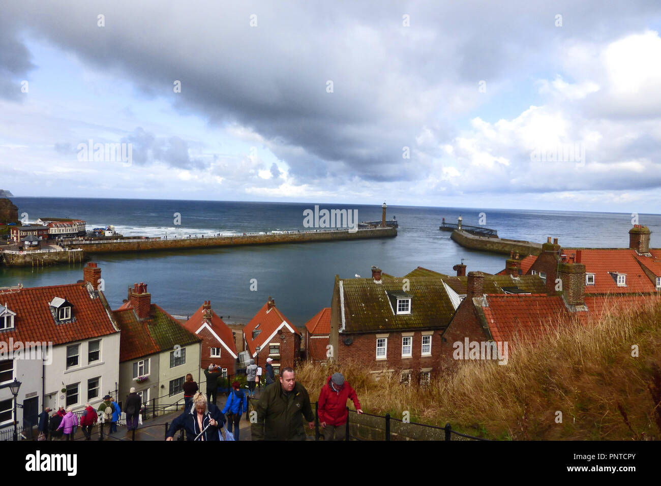 The steps up to the Abbey and view of the harbour entrance at Whitby, Yorkshire with rain threatening Stock Photo