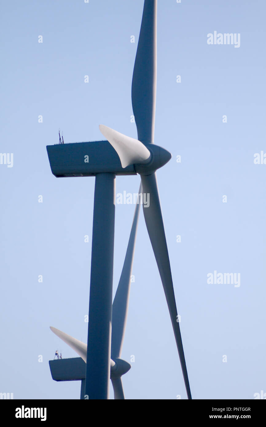 Pico Gallo, Tineo, Asturias. Backlit view of blades, rotor hub and nacelle of a couple of wind mills and blue sky in the background. Stock Photo