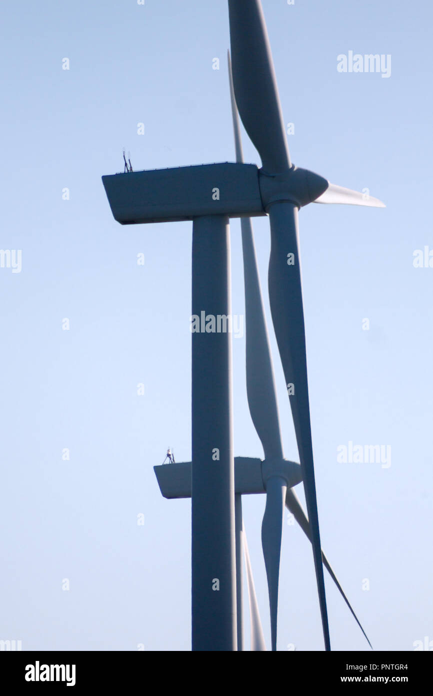 Pico Gallo, Tineo, Asturias. Backlit view of blades, rotor hub and nacelle of two wind mills and blue sky in the background. Stock Photo