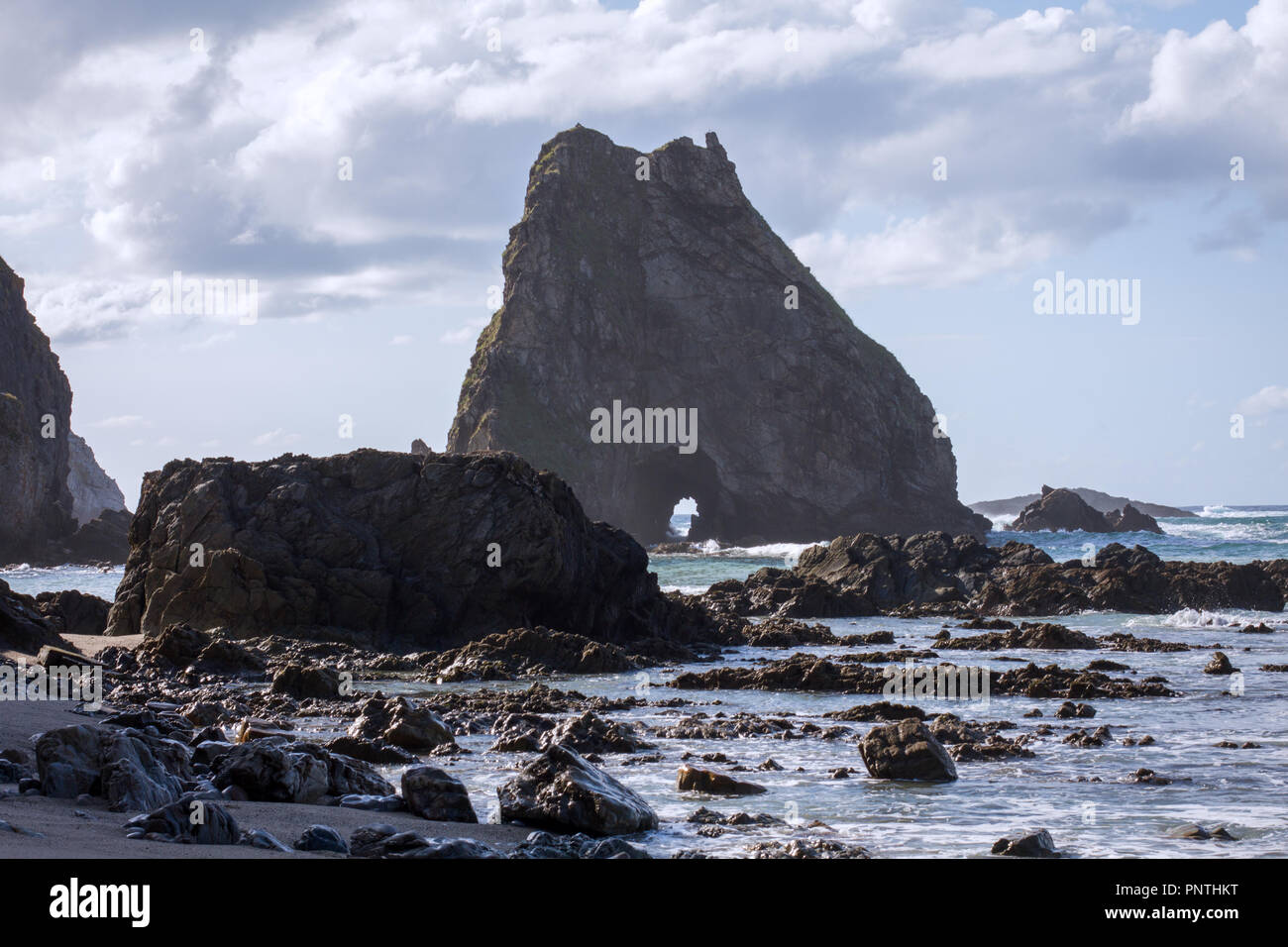 Asturias, Spain. View from the beach of a mysterious dark island with a cave in it. Stock Photo