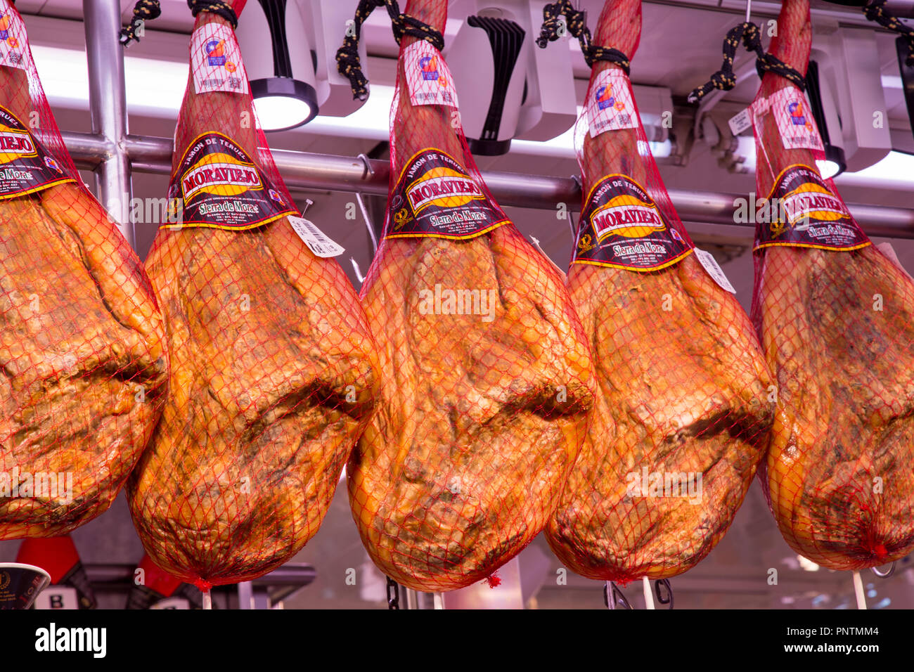 CUred ham legs hanging in Mercat Central, the central market in Valencia city, Spain Stock Photo