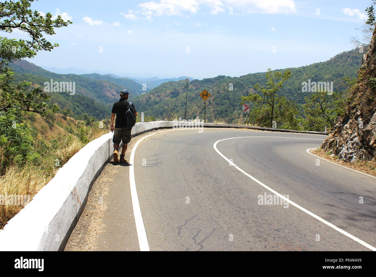 a man is walking a serpentine road with mountain view Stock Photo