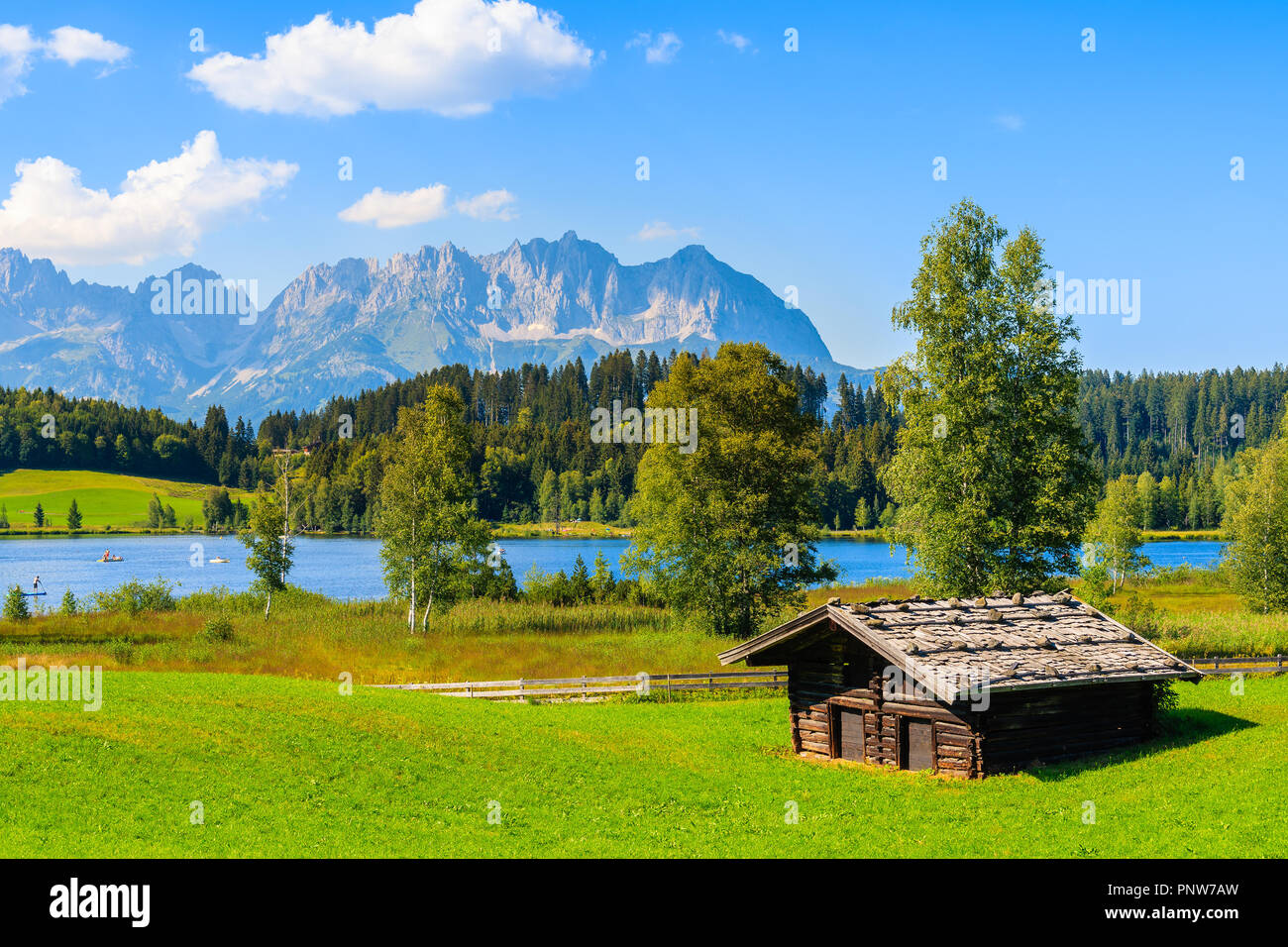 Wooden hut on green meadow against Alps mountains near Schwarzsee lake on sunny beautiful summer day near Kitzbuhel, Tyrol, Austria Stock Photo