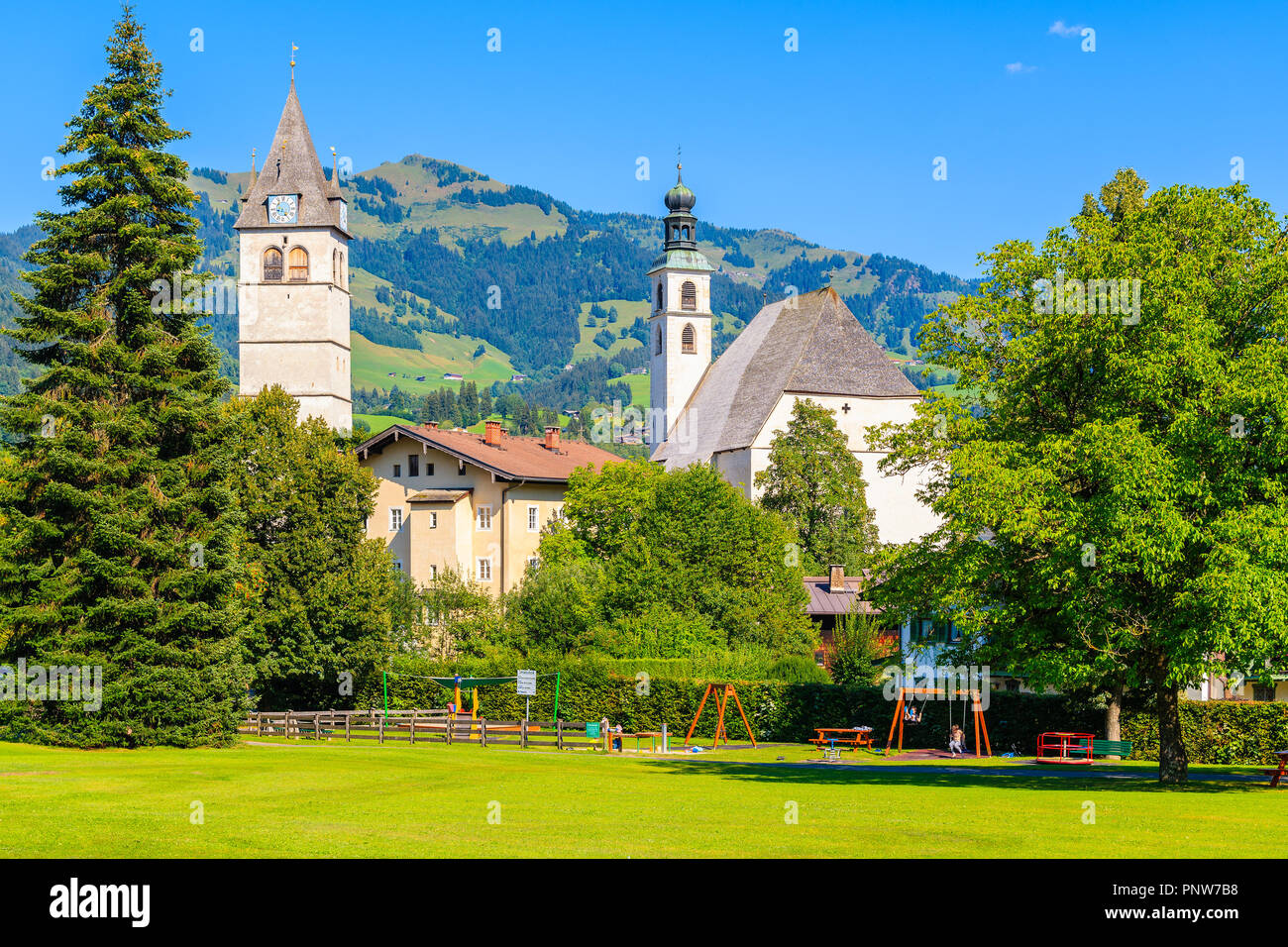 KITZBUHEL TOWN, AUSTRIA - JUL 30, 2018: Church towers in Kitzbuhel town park against sunny blue sky in summertime. It is one of the most famous Austri Stock Photo