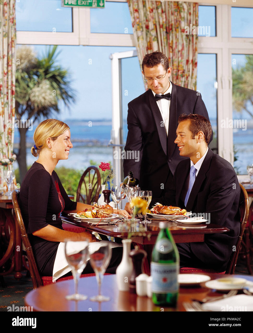 Waiter serving couple dining at hotel. British Channel Islands. Guernsey. Herm. Stock Photo