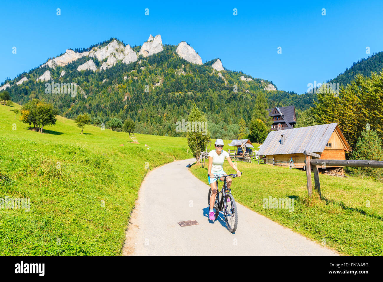 Young woman cycling near Trzy Korony (Three Crowns) sunny autumn day, Pieniny Mountains, Poland Stock Photo