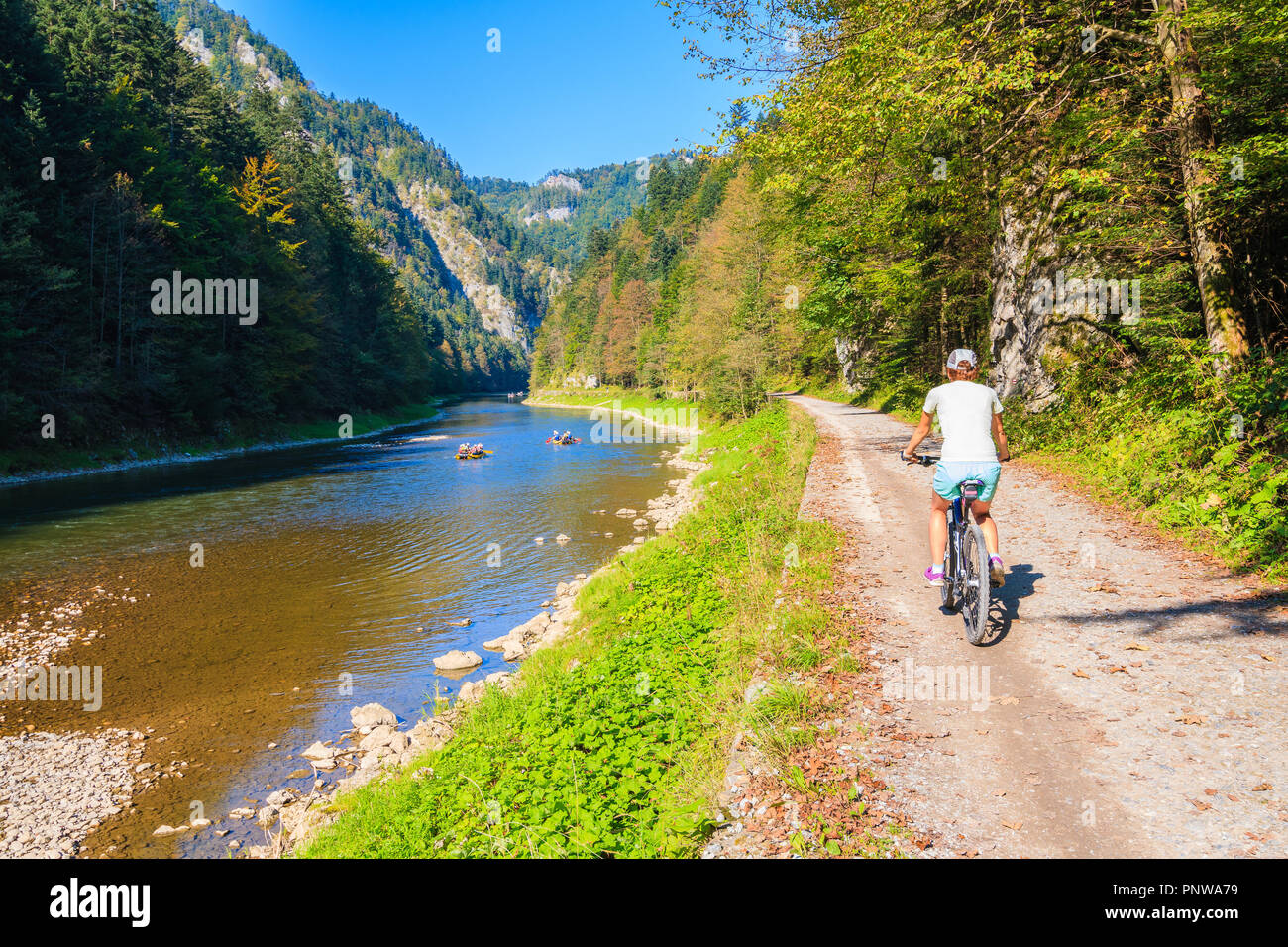 Young woman cycling along Dunajec river on sunny autumn day, Pieniny Mountains, Poland Stock Photo